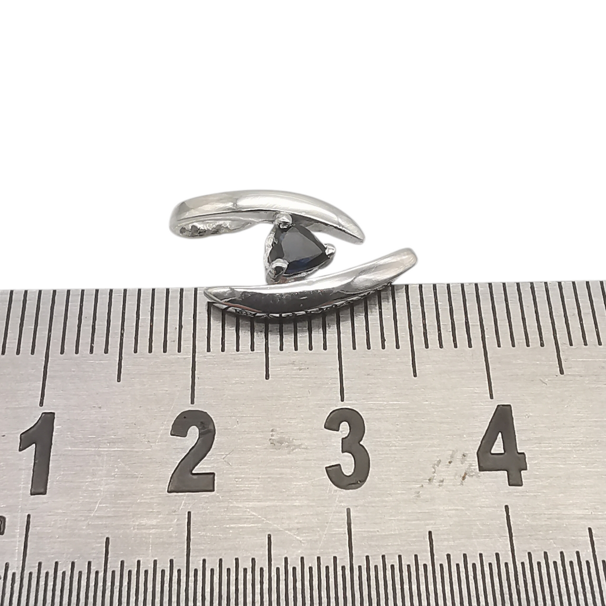 Pendentif BALMAIN en or blanc 18 carats et saphir présenté avec une règle de mesure.
