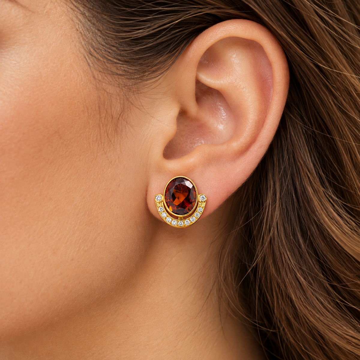 Boucles d'oreilles en or jaune 18 carats avec grenats ovales et diamants portées à l'oreille.