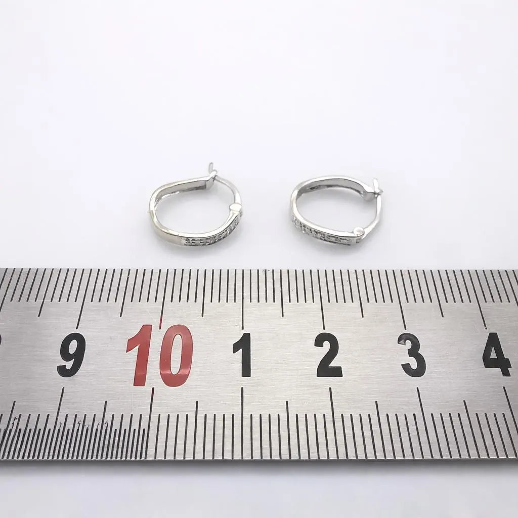 Paire de créoles en or blanc 750 avec diamants, photographiées avec une règle graduée pour montrer leurs dimensions.