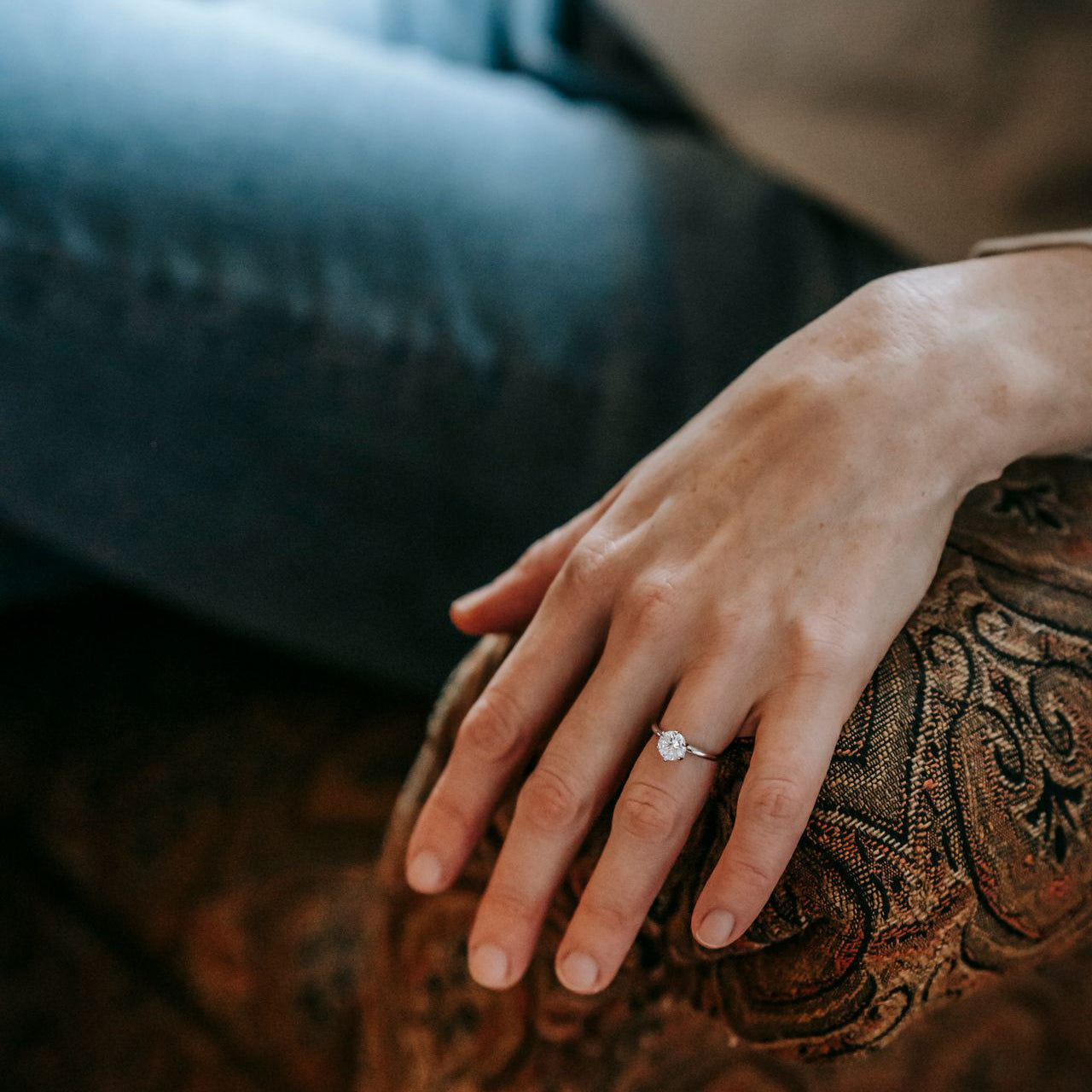 Main portant une bague solitaire sertie d’un diamant