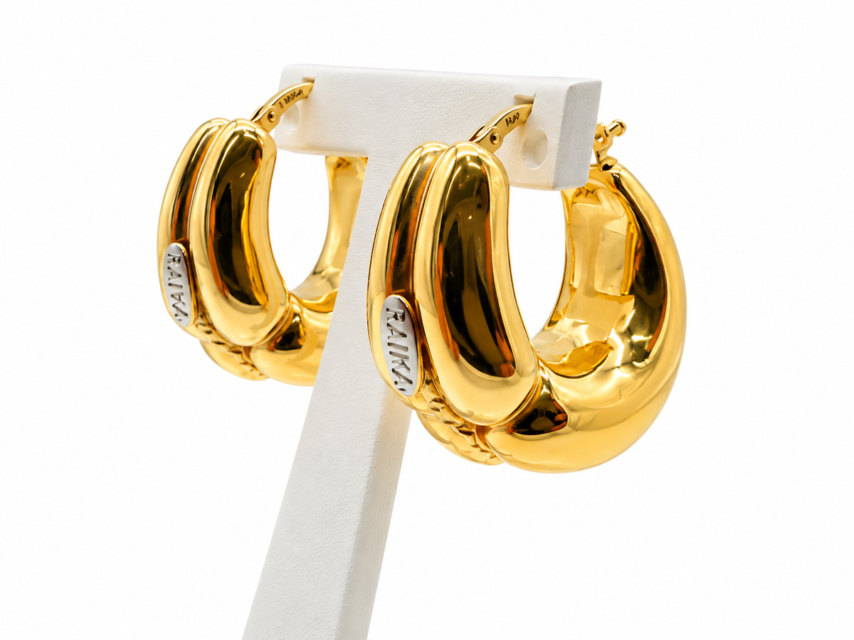 Boucles d’oreilles RAIKA en or jaune 18K présentées sur support, signature visible