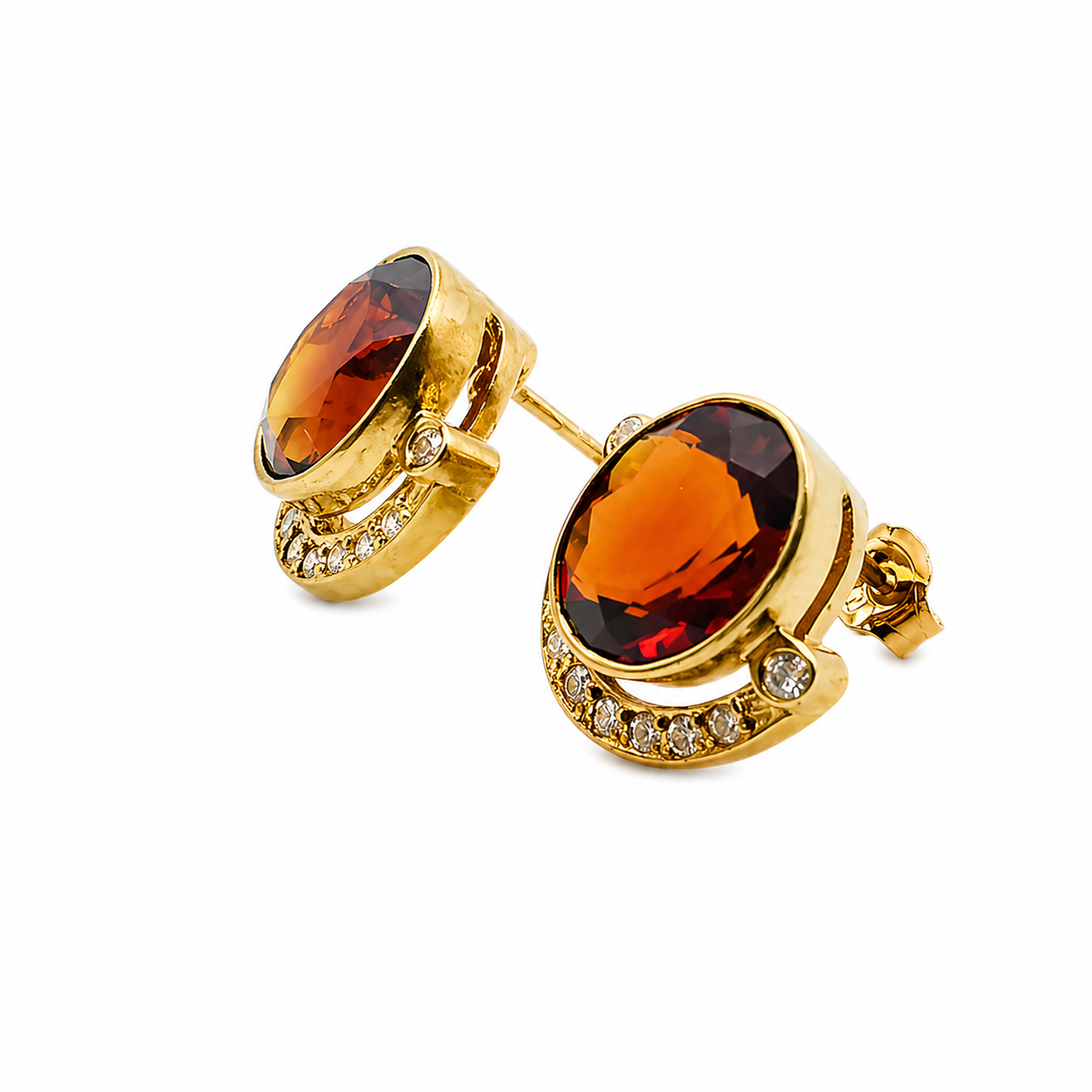 Vue rapprochée des boucles d'oreilles en or jaune avec grenats rouge orangé.