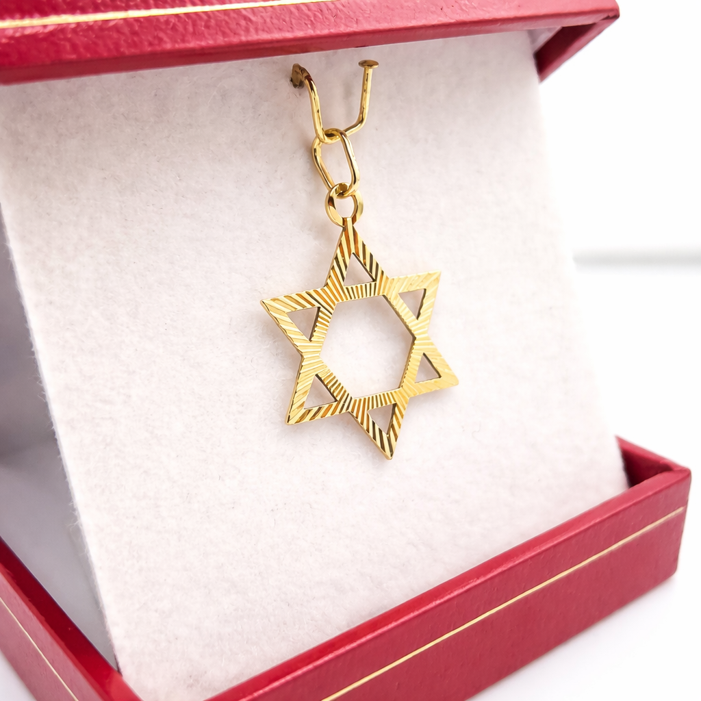 Pendentif Étoile de David en or jaune 18 carats présenté de trois quarts dans son écrin, avec bélière et détails striés visibles.