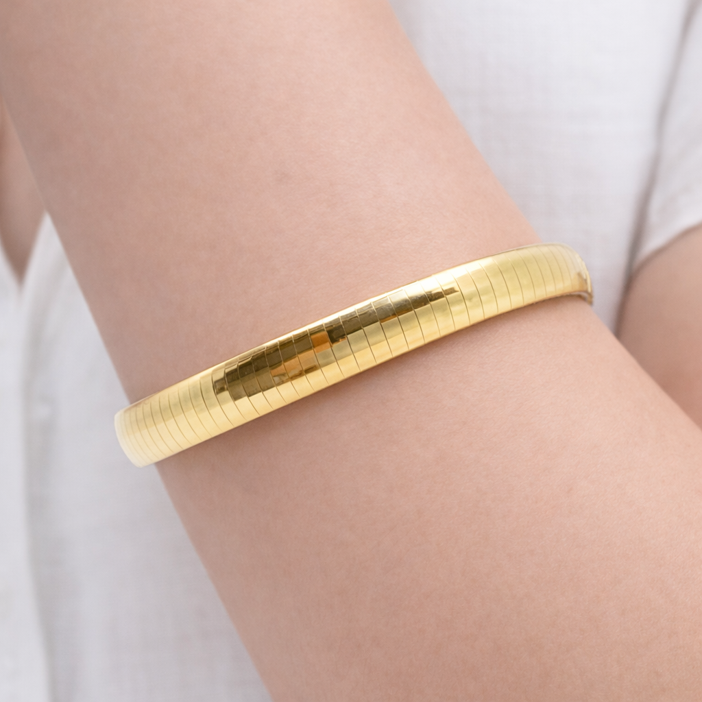 Poignet portant un bracelet maille Oméga en or jaune 18 carats