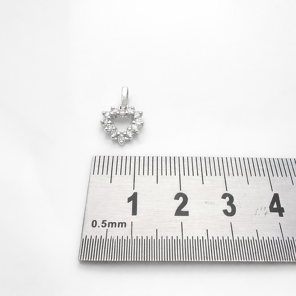 Pendentif cœur en or blanc 18 carats et diamants photographié avec une règle graduée.