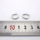 Paire de créoles en or blanc 750 avec diamants, photographiées avec une règle graduée pour montrer leurs dimensions.