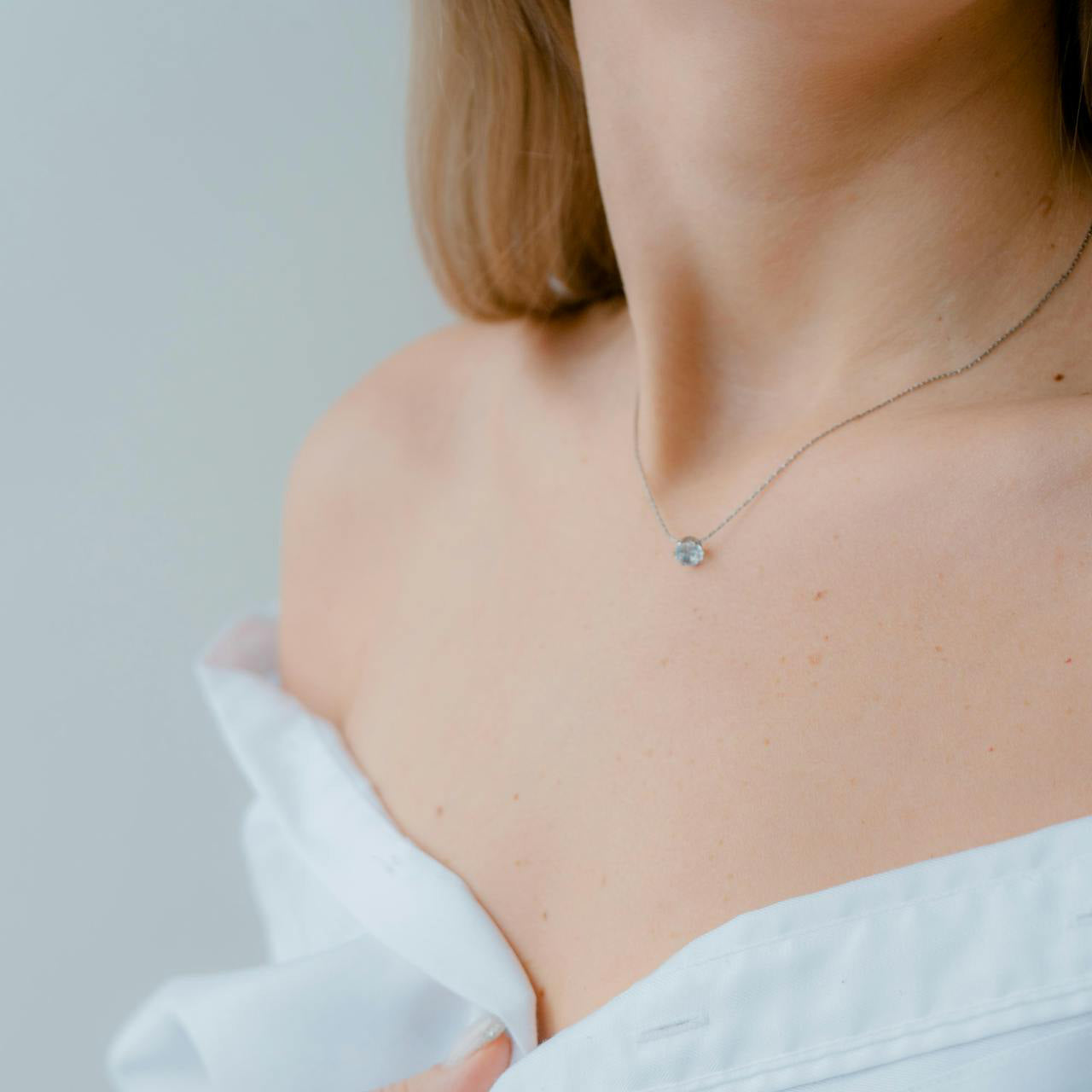 Femme portant un collier fin avec pendentif serti