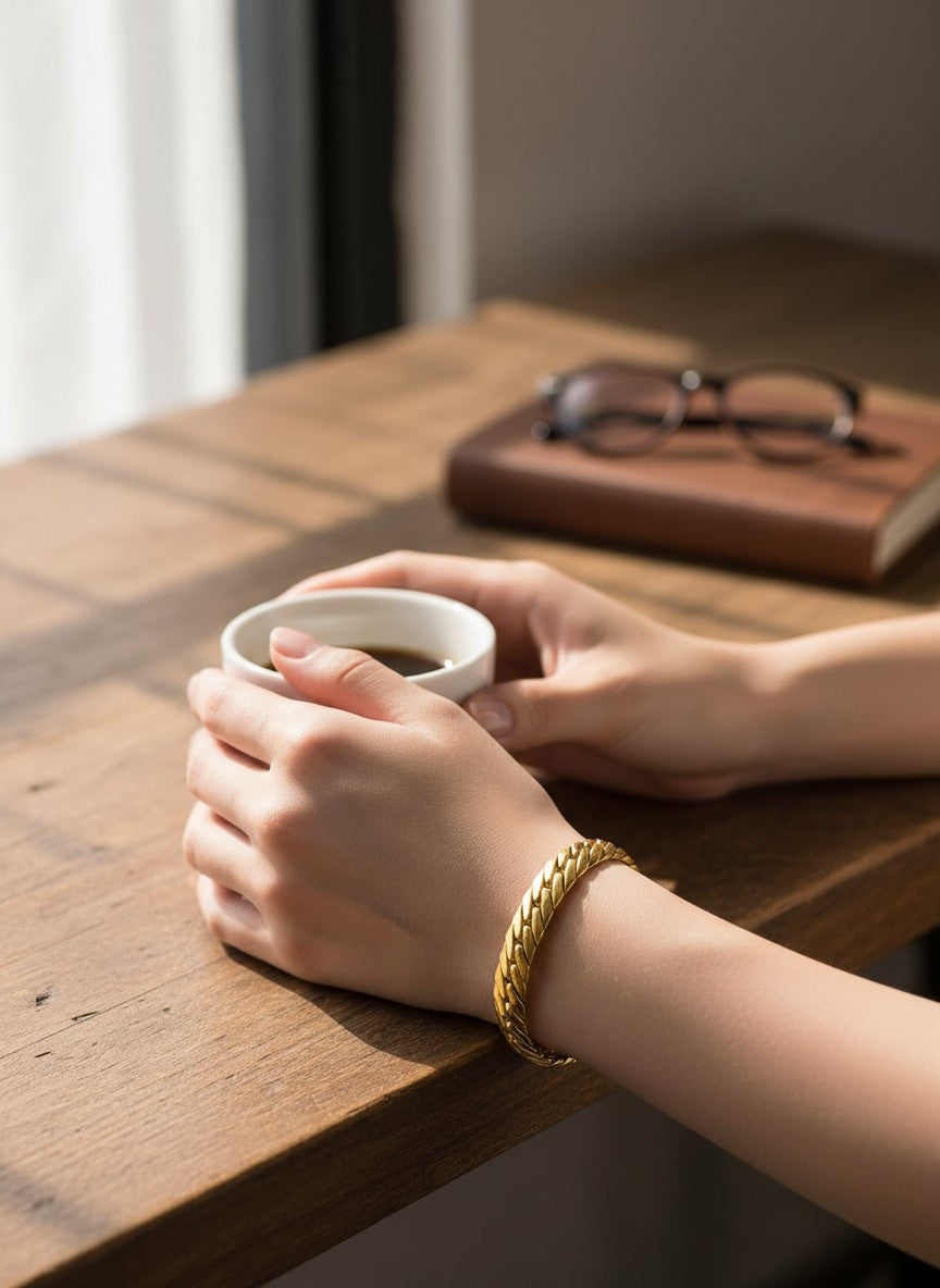 Main tenant une tasse et portant un bracelet torsadé en or jaune 18 carats